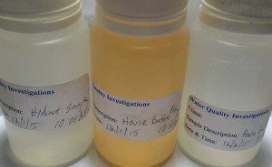 Three different colored water sample collection bottles from a hydrant